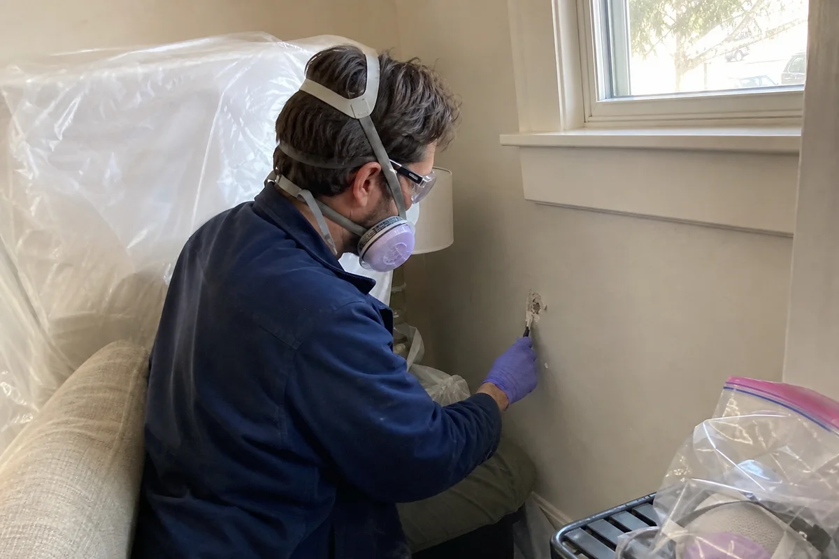 Inspector taking material sample from older home wall