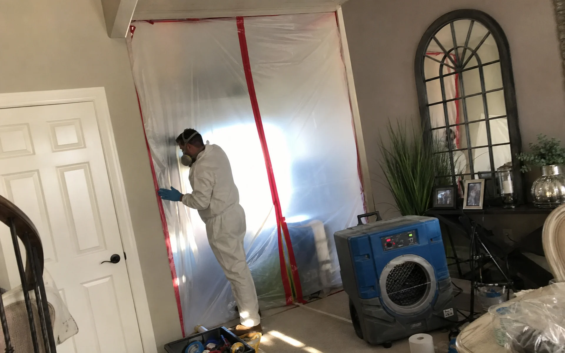 Certified mold remediation technician in PPE behind containment