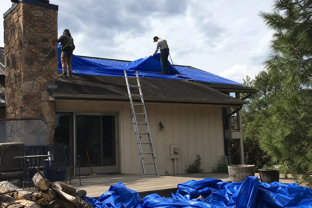 Crew installing emergency tarp over storm-damaged roof