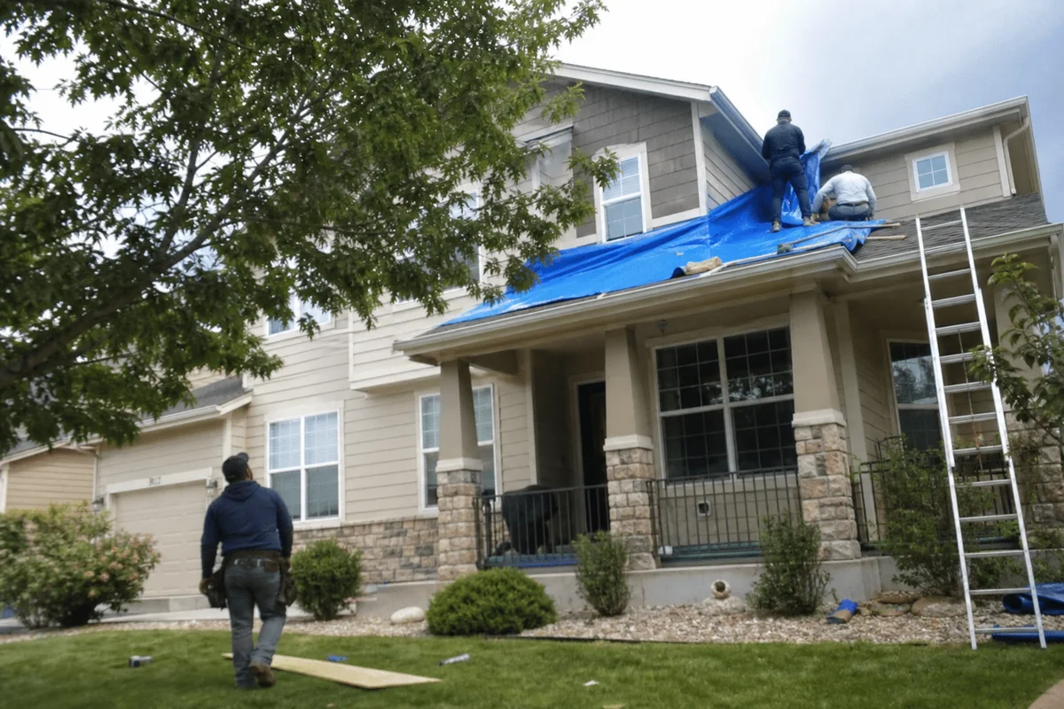 Restoration crew installing emergency roof tarp