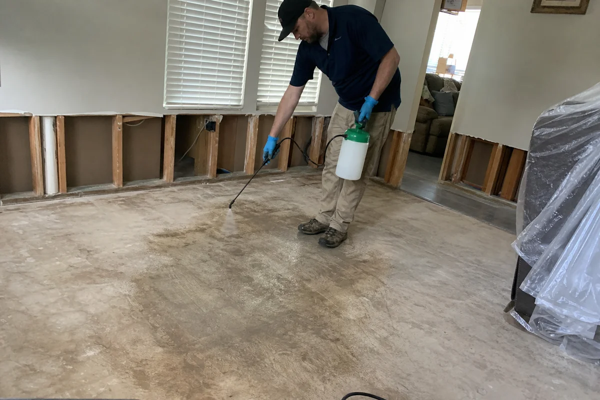 Technician applying antimicrobial disinfectant to subfloor